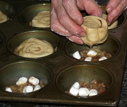 Place Bun for Coconut Glazed Sticky Buns on Top of Frosting and Marshmallows